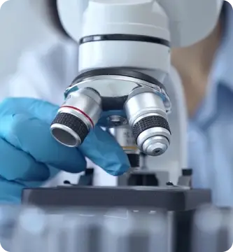 Cientista utiliza microscópio em laboratório, representa o compromisso do Einstein com a pesquisa científica, inovação e avanços na área da saúde para promover tratamentos e diagnósticos de excelência.
