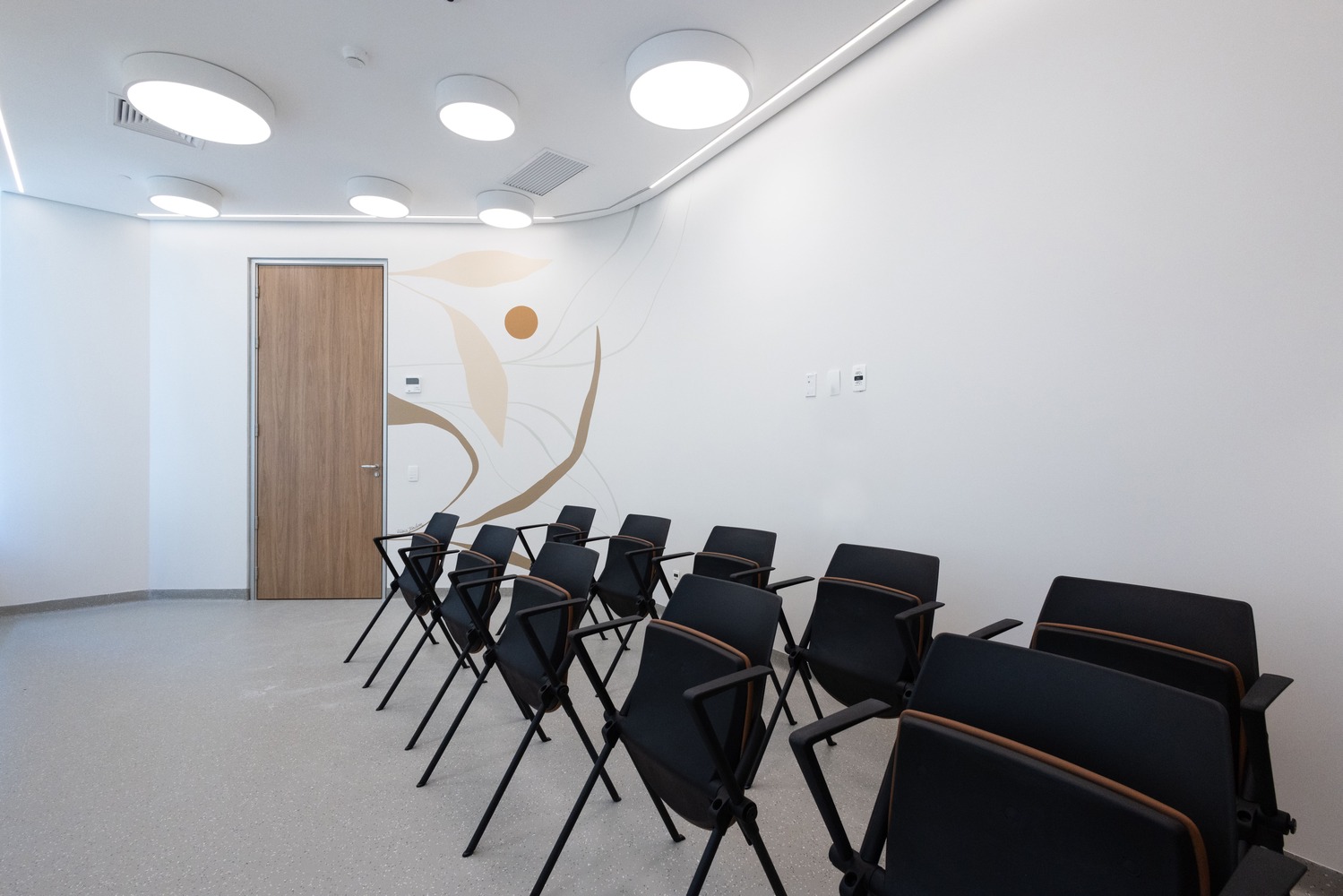 Imagem de sala para terapias. A sala é organizada com várias cadeiras dispostas em duas fileiras lado a lado. O ambiente é acolhedor e preparado para proporcionar um espaço seguro e confortável para as sessões de terapia em grupo.