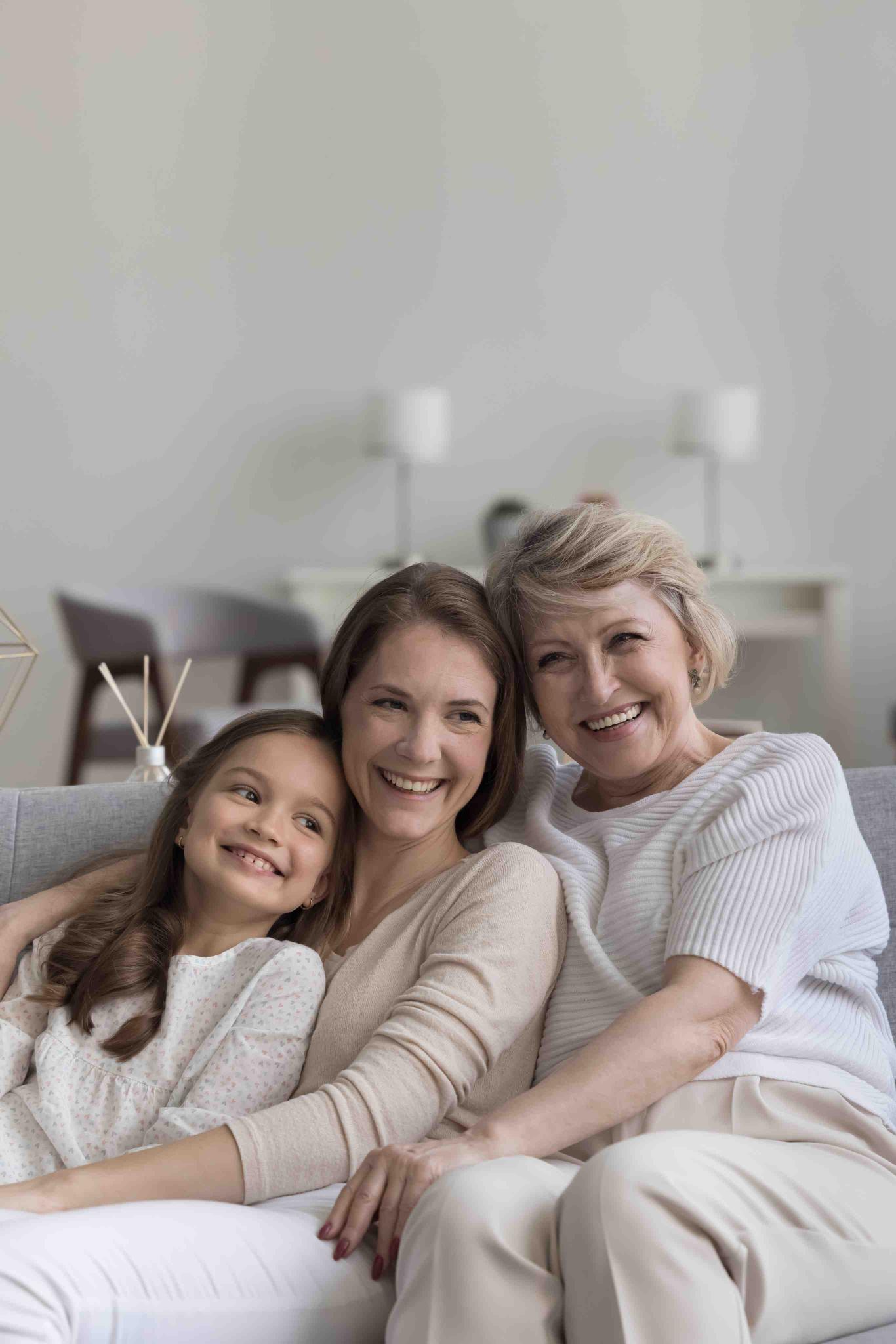 Criança, mulher e idosa sorrindo juntas em casa, representando bem-estar e saúde mental em diferentes fases da vida Criança, mulher e idosa sorrindo juntas em casa, representando bem-estar e saúde mental em diferentes fases da vida