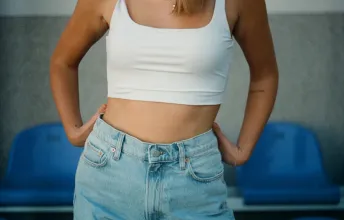 Pessoa de corpo magro vestida com uma calça jeans e uma regata branca